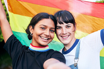 Portrait, lesbian and couple with flag for pride, freedom and happy or bonding at festival. Face,...