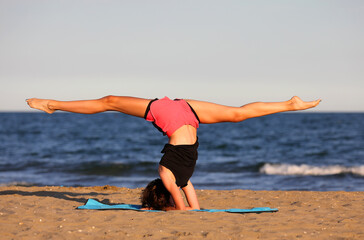 girl does exercises on the beach in summer