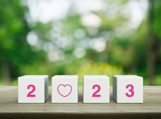 Love icon with 2023 letter on white block cubes on wooden table over blur green tree in park, Happy new year 2023 and Valentines day concept