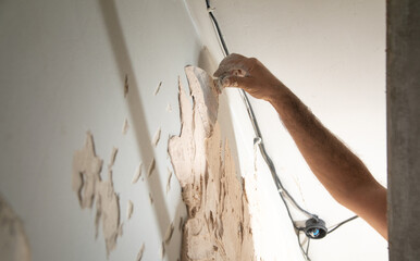 Man is applying putty on a wall. Renovating house