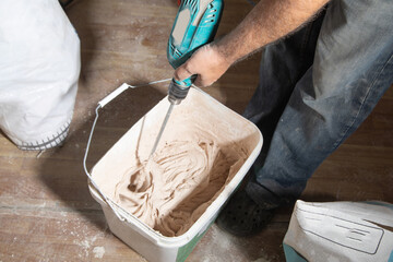 Builder mixes gypsum putty in a bucket.