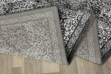 Specially designed carpet, laid on the floor and curled. Detail. White lace on a wooden background. 