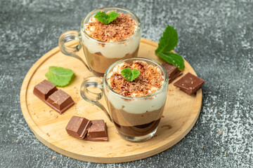 Mousse Three chocolates in a glass decorated with mint on a light background. Layered delicious dessert. place for text, top view