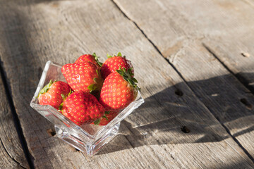 木のテーブルの上に置かれたガラスの器に入ったイチゴ