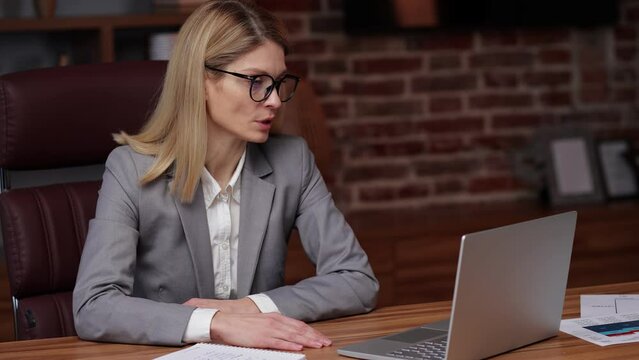 Focused female executive manager having virtual meeting working on laptop computer giving online training, remote class on video conference call.