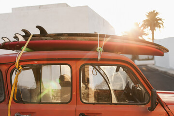 A stack of surfboards on a retro car roof with sun shining. Summer and surf background wallpaper.  