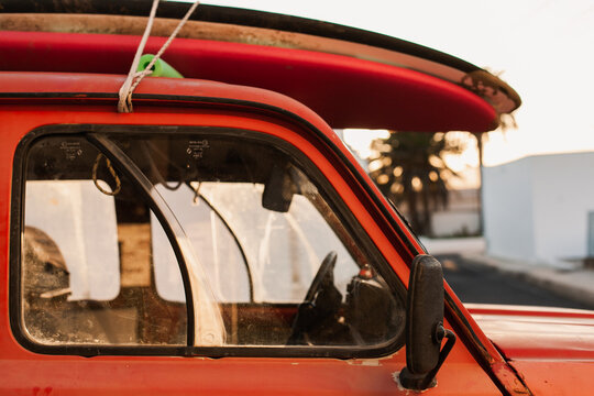 A stack of surfboards on a retro car roof with sun shining. Summer and surf background wallpaper.  