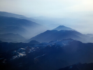Mountains in the haze. View of the beautiful high mountains from the plane.