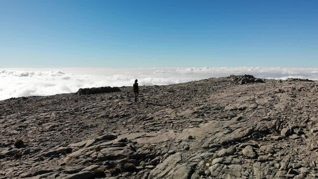 4K drone footage over woman walking on a rocky peak with sea of clouds on the back at La Maroma summit, Malaga, Spain.
Mid angle, traveling movement.