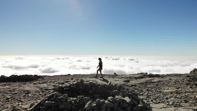 4K drone footage over woman walking on a rocky peak with sea of clouds on the back at La Maroma summit, Malaga, Spain.
Mid angle, traveling movement.