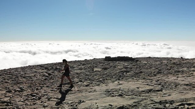 4K drone footage over woman walking on a rocky peak with sea of clouds on the back at La Maroma summit, Malaga, Spain.
Mid angle, traveling movement.