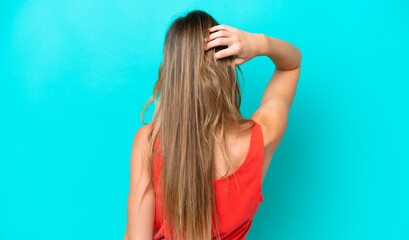 Young caucasian woman isolated on blue background in back position and thinking