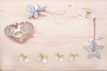 Happy New Year. New Year's card and copy space. Wooden heart, New Year's toys and different bows as decoration. Background - textured wooden surface made of light wood.