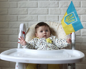 A little girl holds the flag of Ukraine in her hands. Young patriot, blue and yellow flag. A free Ukrainian woman