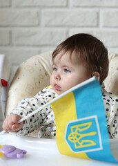 A little girl holds the flag of Ukraine in her hands. Young patriot, blue and yellow flag. A free Ukrainian woman