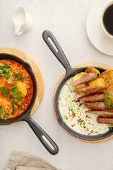 Top view on two pan dishes with sausages and eggs