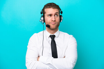 Naklejka premium Telemarketer caucasian man working with a headset isolated on blue background making doubts gesture while lifting the shoulders