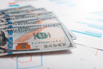 Close-up of money on business documents. Selective focus on one hundred dollar bills, low angle view