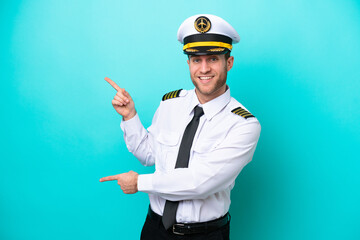 Airplane caucasian pilot isolated on blue background pointing finger to the side and presenting a...