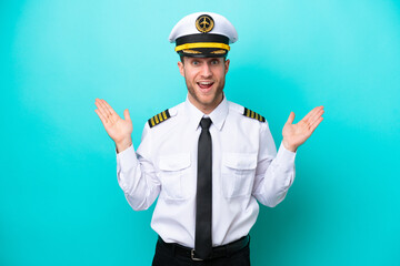 Airplane caucasian pilot isolated on blue background with shocked facial expression