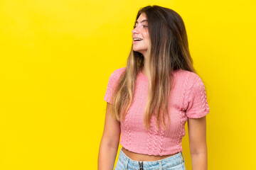 Young caucasian woman isolated on yellow background laughing in lateral position