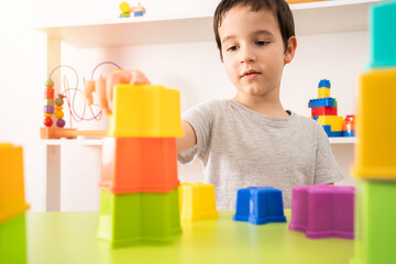 An interested pre-school child building something with plastic blocks.