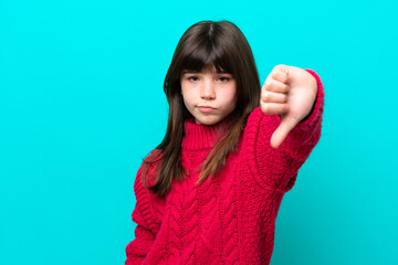 Little caucasian girl isolated on blue background showing thumb down with negative expression