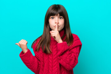 Little caucasian girl isolated on blue background pointing to the side and doing silence gesture