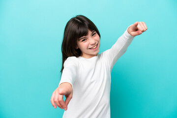 Fototapeta premium Little caucasian girl isolated on blue background pointing front with happy expression