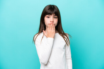 Little caucasian girl isolated on blue background covering mouth with hand