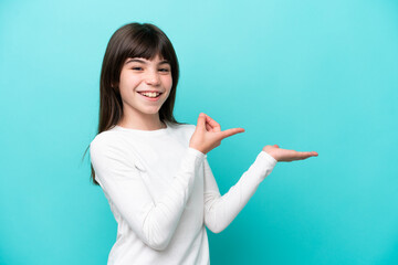 Little caucasian girl isolated on blue background holding copyspace imaginary on the palm to insert...