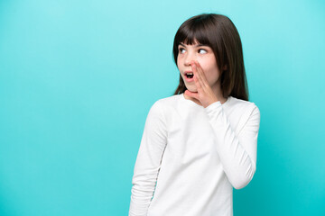 Little caucasian girl isolated on blue background whispering something with surprise gesture while...