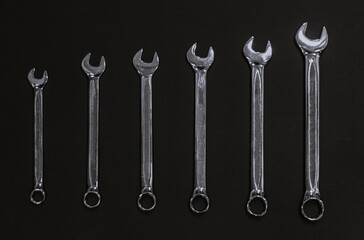 A set of wrenches made of chrome steel on a dark background lined up tools for repair and...