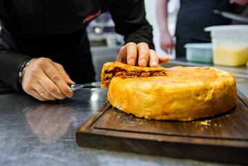 chef hand cut meat pie on restaurant kitchen