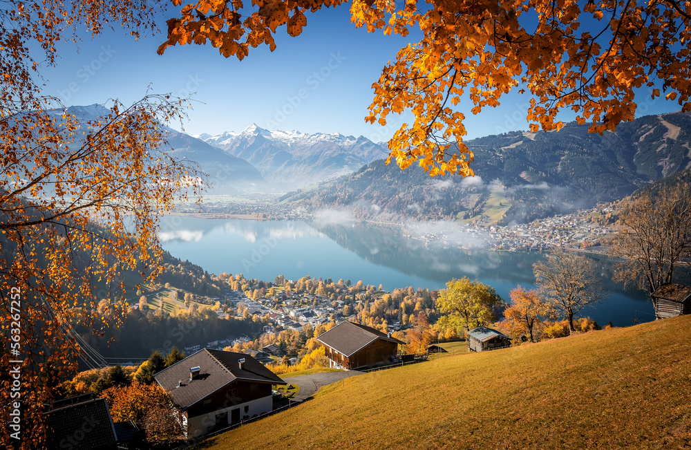 Fototapete Colorful misty morning in the Alps mountains. autumn foggy scenery. Amazing nature background. Mountainous autumn landscape. Red folliage on trees and fog in the distant valley. Zell am see lake
