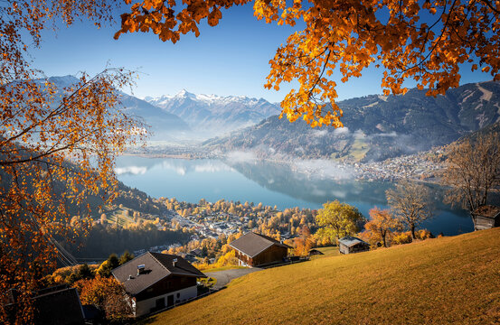 Colorful misty morning in the Alps mountains. autumn foggy scenery. Amazing nature background. Mountainous autumn landscape. Red folliage on trees and fog in the distant valley. Zell am see lake