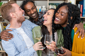 Multiracial group of people drinking wine, close up shot of friends toasting at a dinner party and having fun