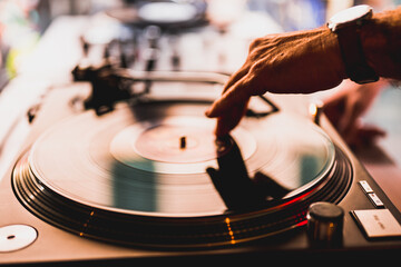 Dj hands on equipment deck and mixer with vinyl record at party, human hands using two vinyl turn...