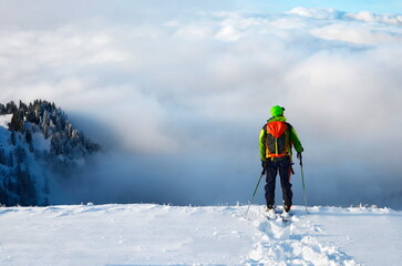 Tourengeher auf Skitour am Gipfel mit Aussicht ins Tal i Nebel und Wolken