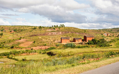 Typical Madagascar landscape - green and yellow rice terrace fields on small hills with clay houses in region near Behenjy