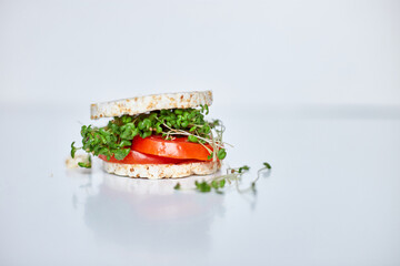 Healthy burger with crispy rice bread vegetables tomato and microgreens on white background, vegan...