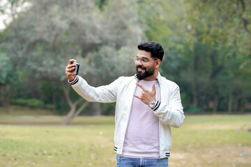 Young indian man using smartphone at park