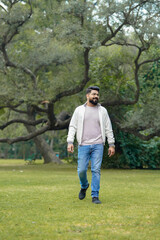 Young and confident indian man giving expression at park.