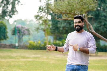 Young and confident indian man giving expression at park.