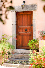 Wood door and windows with wooden shutters on pink colored wall