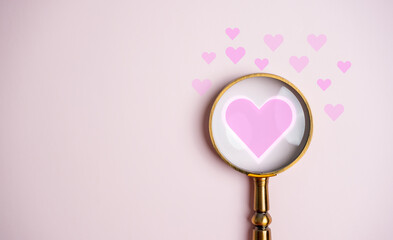 Magnifier focus to pink heart shape icons. love symbol with copy space, couple people, banner, Valentine's day concept.