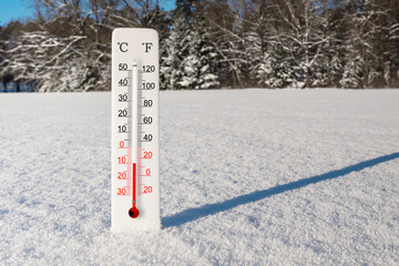 White celsius and fahrenheit scale thermometer in snow. Ambient temperature minus 10 degrees celsius