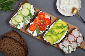 Healthy sandwiches with white cottage cheese, cucumber, arugula, avocado, tomato and radish.