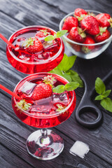strawberry cocktail with ice and fresh mint on a black wooden table