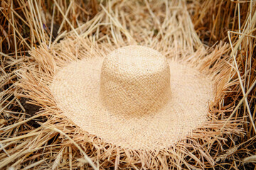 A beige straw hat lies on the ears of wheat. Wheat field. Abstract rural background.